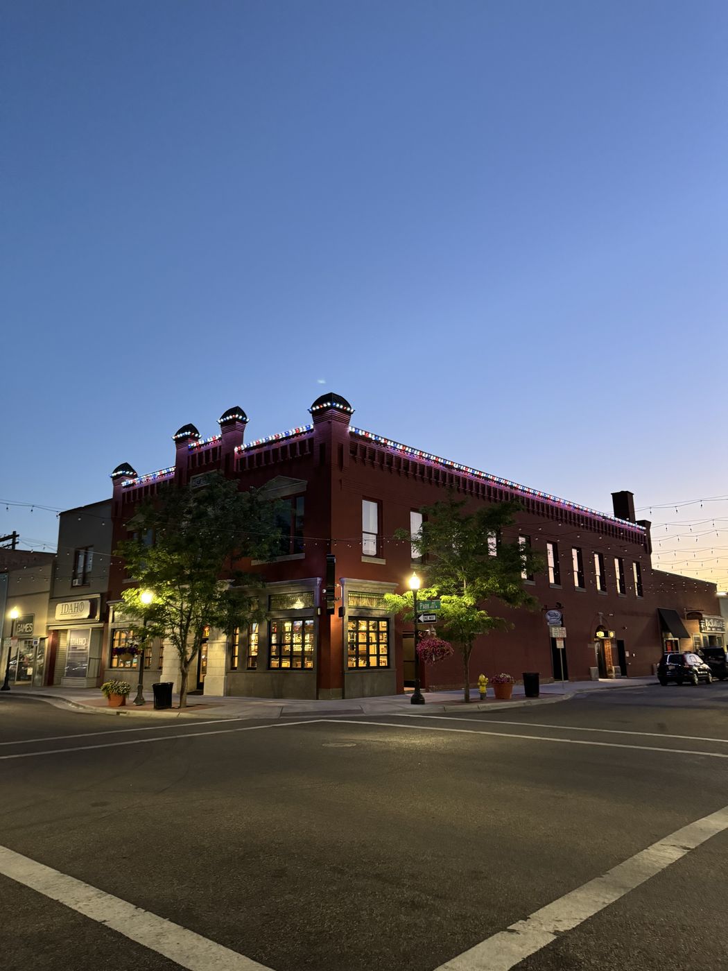 Historic two-story brick building downtown with red, white, and blue permanent lighting along the parapet at dusk