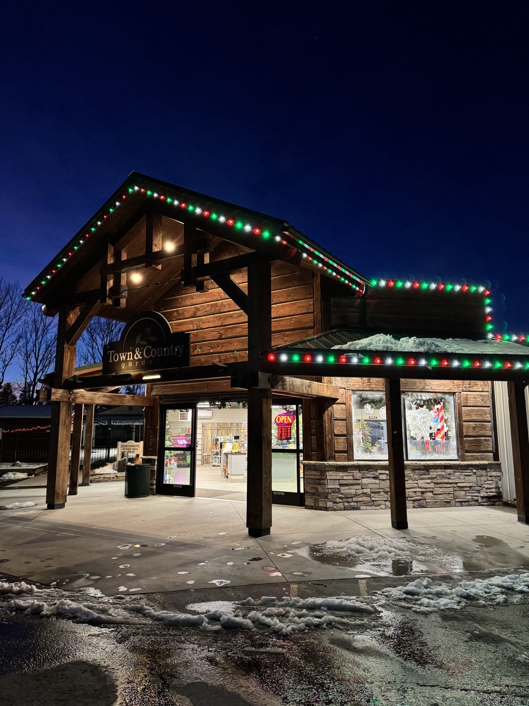 Garden center entrance with red, green, and white holiday lighting at dusk